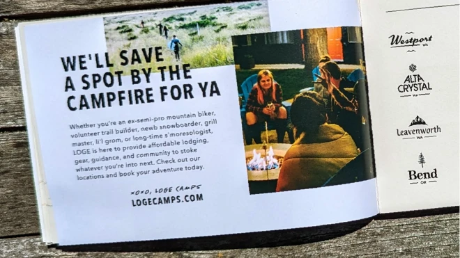 A page from a LOGE Camps brochure against a rustic wooden surface. The page headline reads "We'll save a spot by the campfire for ya," and images of people enjoying a campfire and outdoor activities next to a list of the different LOGE locations.