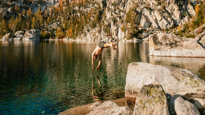 Two people relaxing on inner tubes in a calm river surrounded by dense forest and green hills