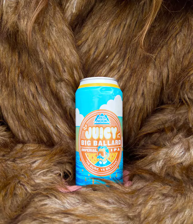 A can of Redhook Juicy Big Ballard Imperial IPA held against a thick brown fur backdrop, highlighting its colorful design.