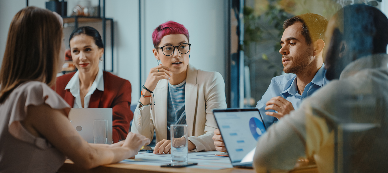 A small group of three professionals in a meeting space discussing AI services.